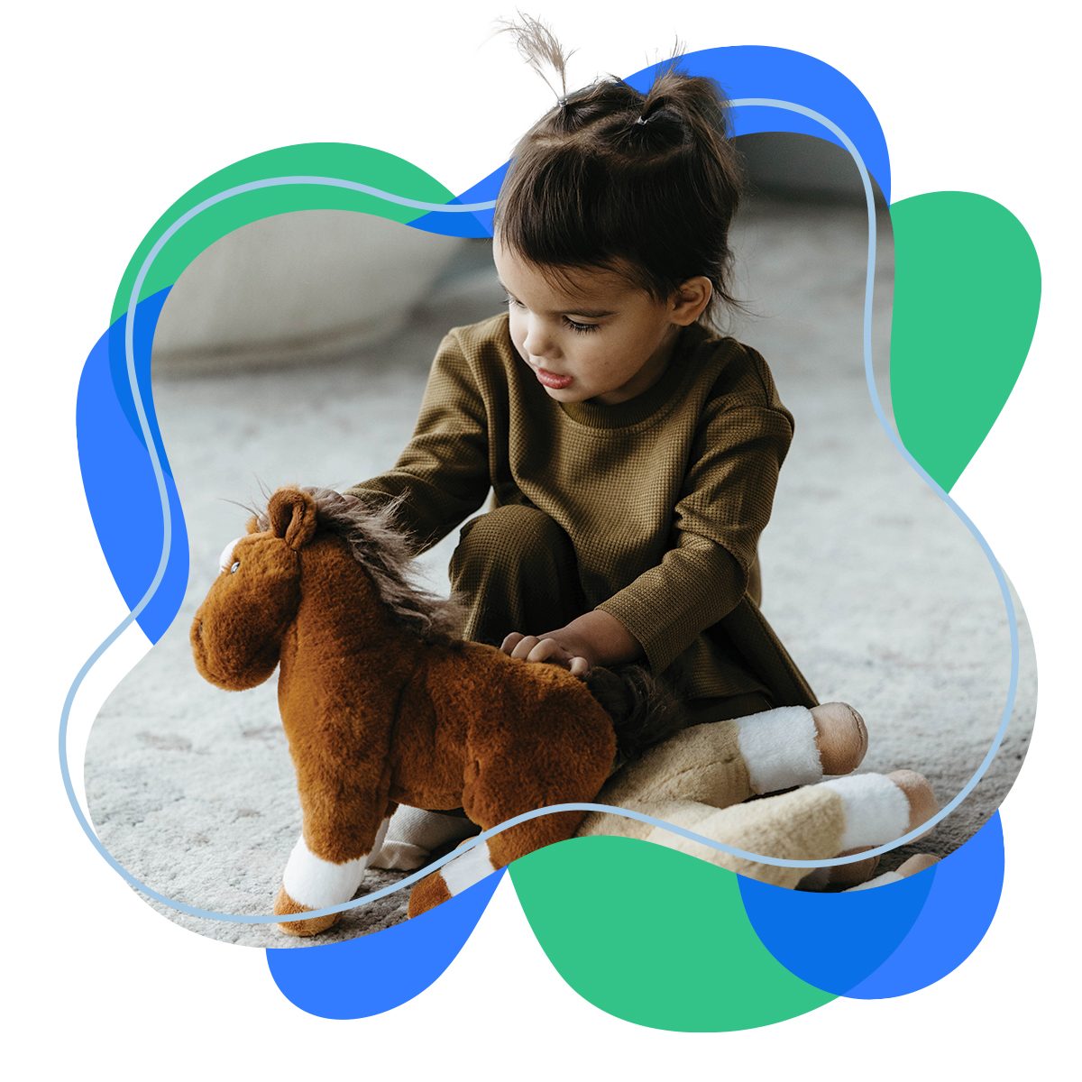 A boy sitting on the floor holding a Zoologee horse plush toy