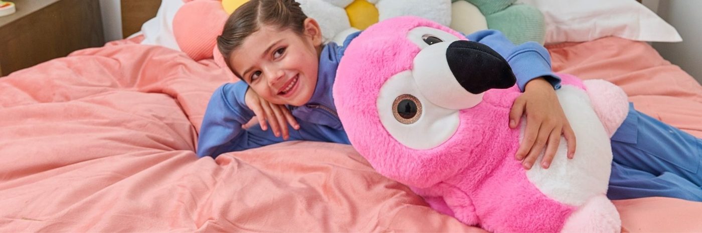 A child in bed with a pink flamingo plush toy