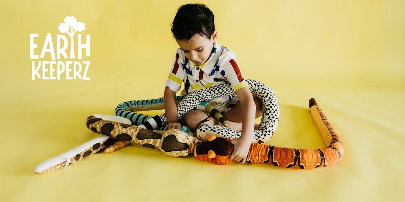 An Earth Keeperz picture of a boy draped with a long snake plush against a yellow wall