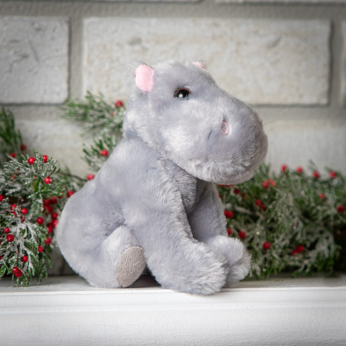 A grey hippo plush toy sitting on a white shelf