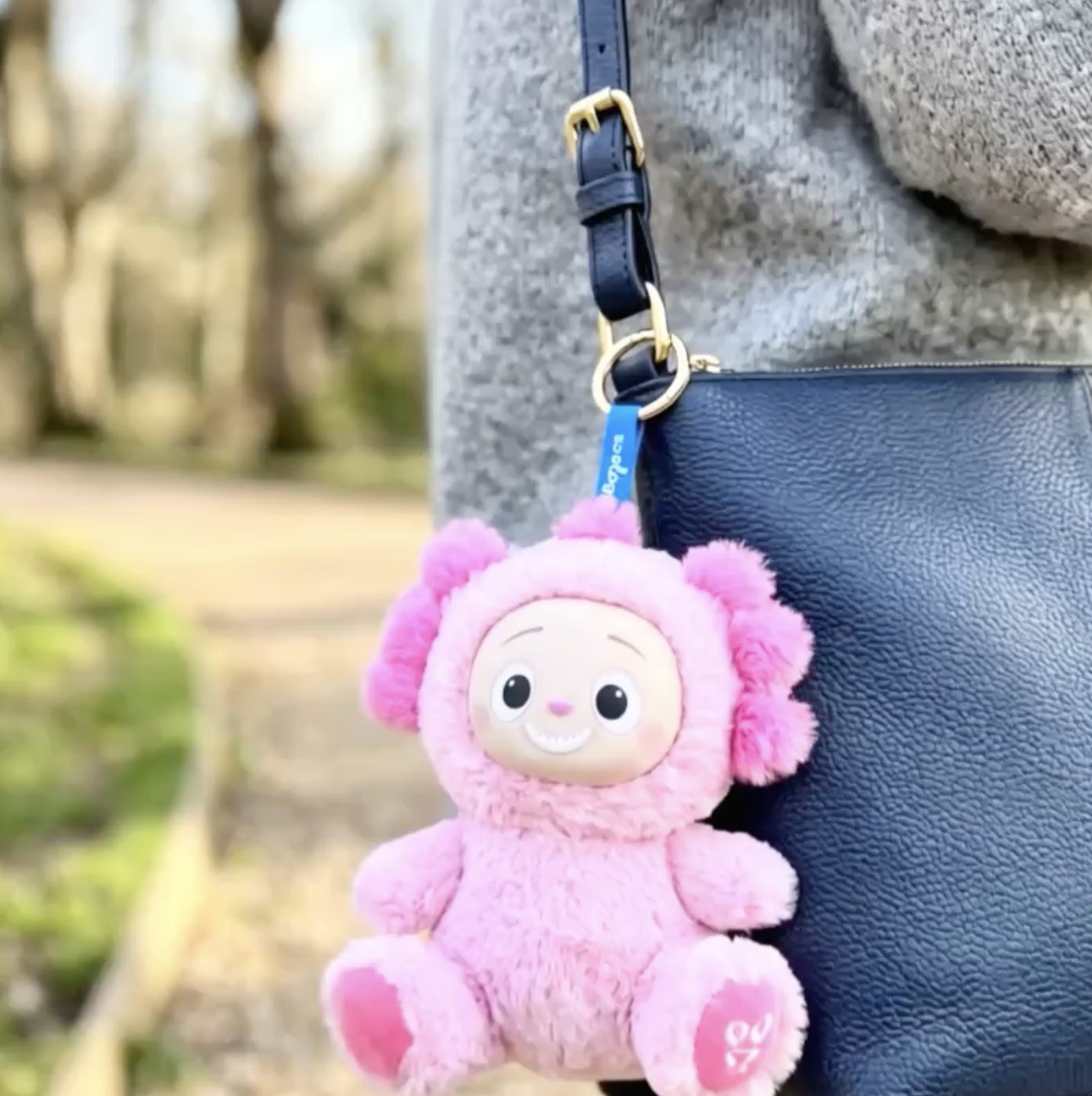 A pink monkey Chummiez plush bag charm clipped to a belt loop